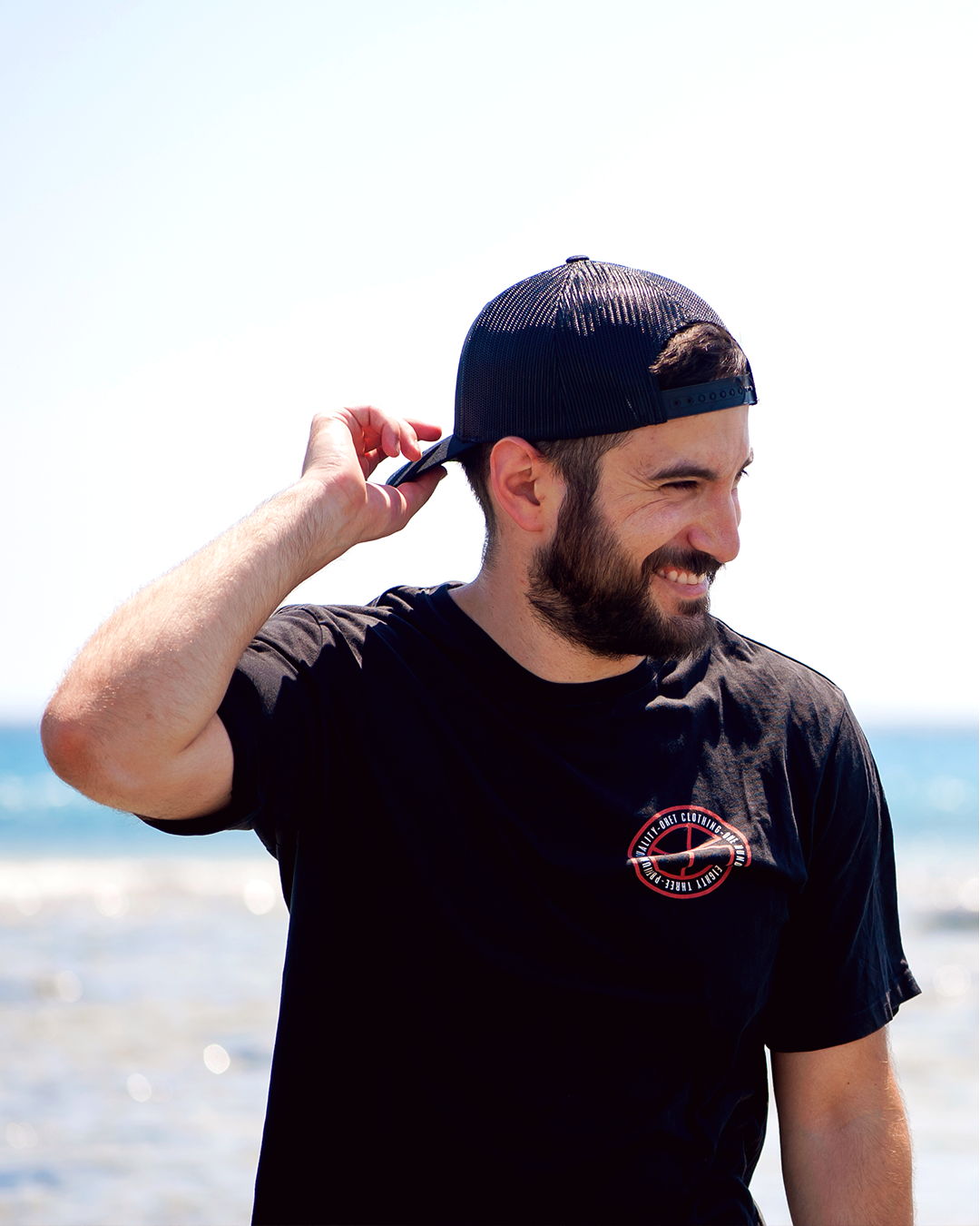 Man laughs at the beach wearing black summer outfit